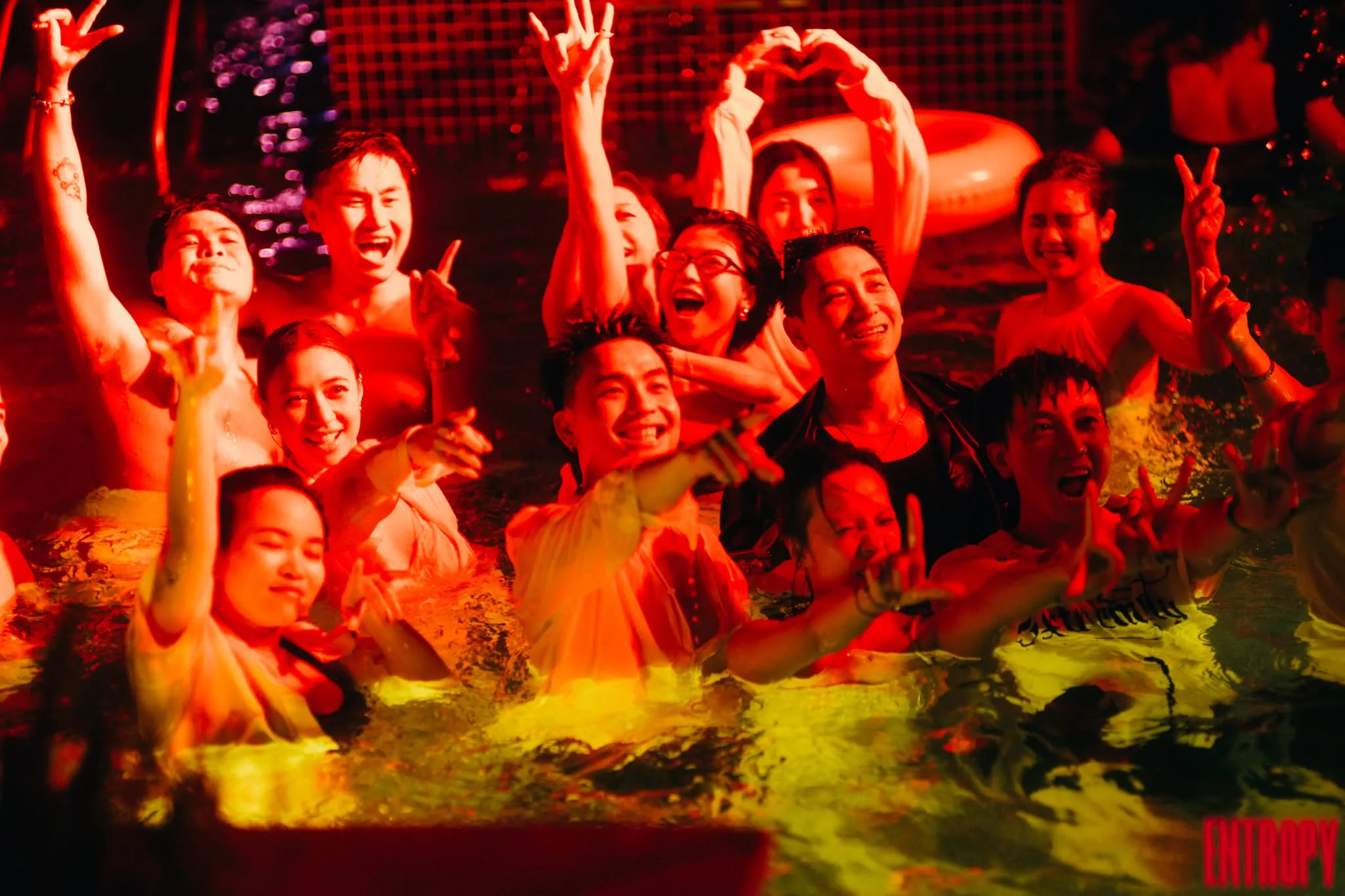 Guests celebrating in the pool at a Fancy after party, lit in red