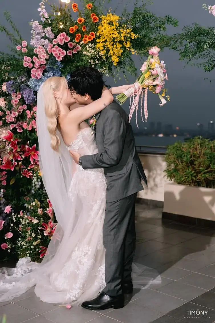 A couple kissing before their clifftop ceremony, chairs set and florals in place