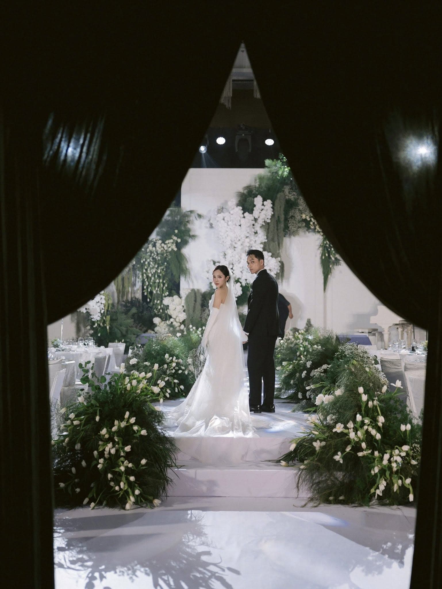 A ceremony aisle under a canopy of white tulips and drifting greenery